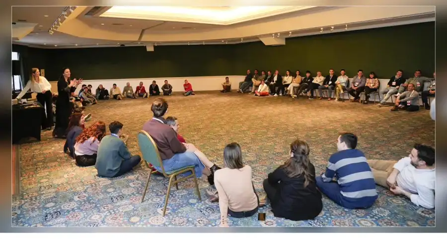 Participantes sentados en una gran ronda en una sala de encuentros.