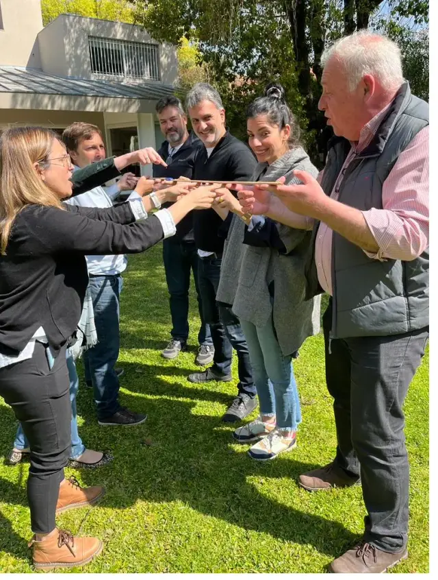 Un grupo coordina sus movimientos en una dinámica de equipo al aire libre.