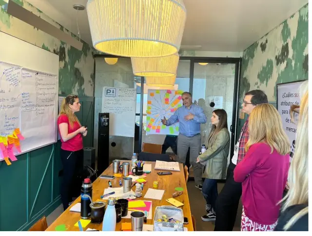 Equipo trabajando con ideas y notas adhesivas en una pizarra durante un taller.